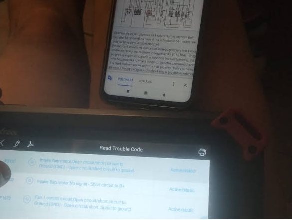 Schemă electrică deschisă pe telefon, alături de testerul care afișează codurile citite