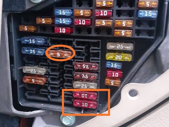 Panou de siguranțe auto, cu două siguranțe încercuite cu marker portocaliu în timpul verificării